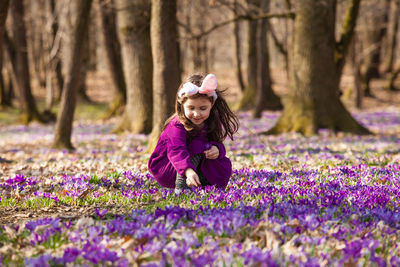 Girl with purple flowers on tree trunk