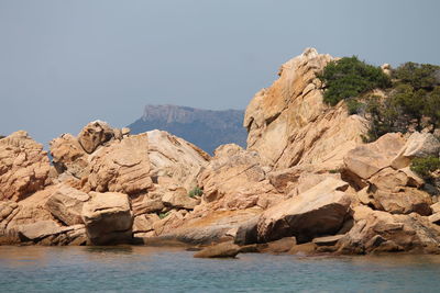 Rock formations by sea against clear sky