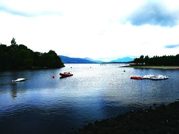 Boats moored in river with mountain range in background