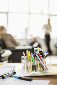 Desk organizer with businesspeople in background at creative office