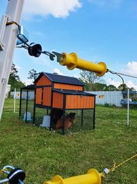 Yellow bird on field against sky