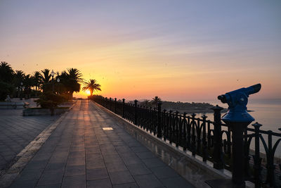 Footpath by sea against sky during sunset