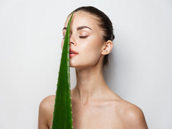 Portrait of young woman making face against white background