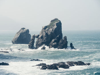 Scenic view of rocks in sea against clear sky