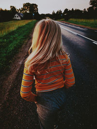 Rear view of woman standing on road