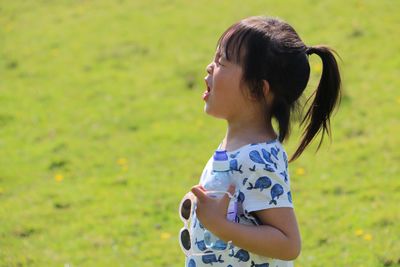 Cute girl crying on grassy field during sunny day