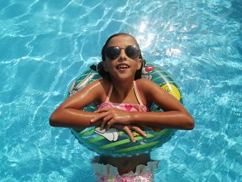 Portrait of girl swimming in pool with sunglasses 