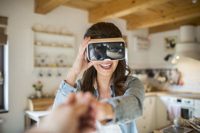 Young woman at home using virtual reality goggles