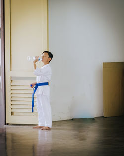 Boy wearing uniform while drinking water in class