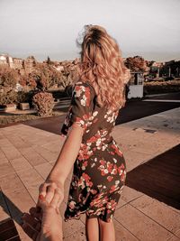 Midsection of woman standing by tree against sky