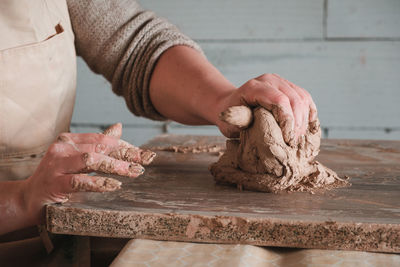 Midsection of person kneading clay on table