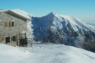 Snow covered houses by mountain against clear sky