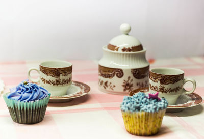 Cupcakes by cups on table