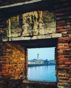 Buildings and sea seen through window on brick wall