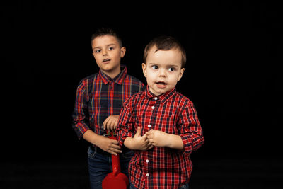 Portrait of boy standing against black background