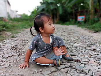 Full length of cute baby girl sitting on stones