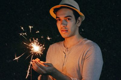 Portrait of man holding sparkler at night
