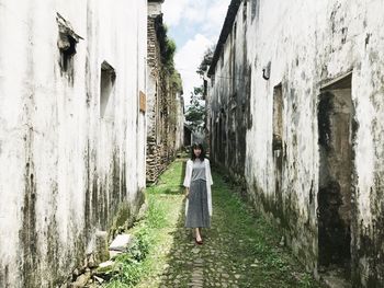 Rear view of woman walking on alley amidst buildings