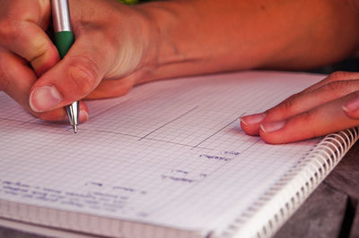 Cropped image of woman writing on book