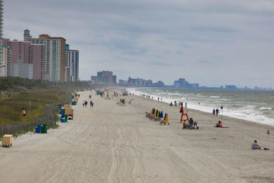 Panoramic view of people on beach against sky