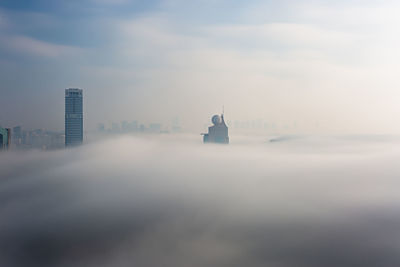 Buildings in city against cloudy sky