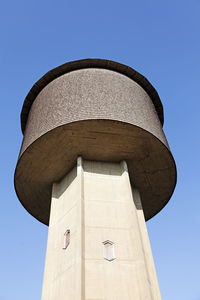 Low angle view of water tower against blue sky