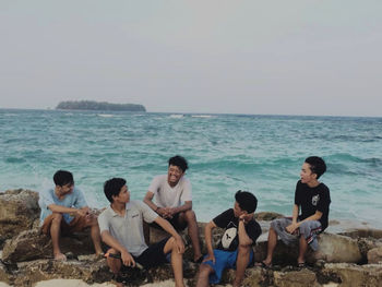 People sitting on beach against sky