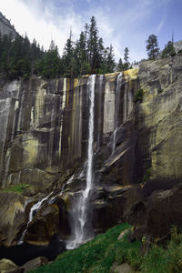 Low angle view of waterfall on rocks against sky