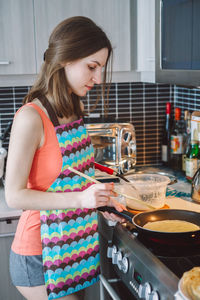 Midsection of woman standing in kitchen at home