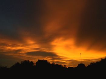 Low angle view of silhouette trees against dramatic sky