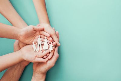 Cropped hand of woman holding pills against blue background