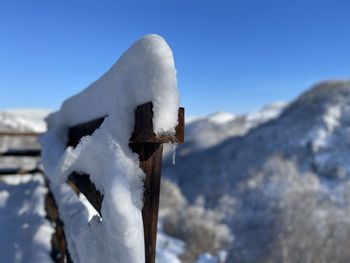 Close-up of snow covered metal against blue sky
