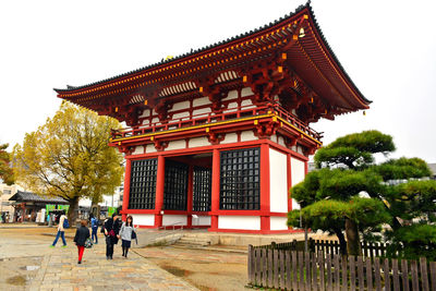 People outside temple building against clear sky