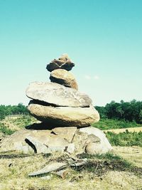 Stack of rocks on field against clear sky