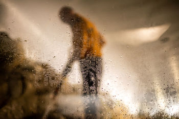 Side view of man seen through wet car window during rainy season