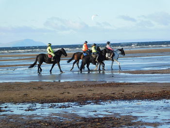 Men running on beach against sky