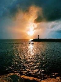 Scenic view of sea against dramatic sky during sunset