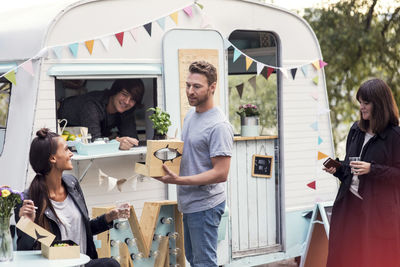 Smiling male owner looking at customers talking outside food truck