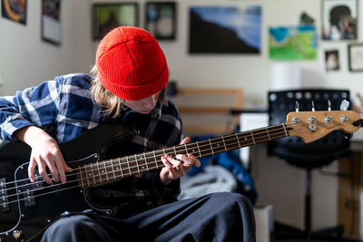 Teenager playing guitar in bedroom as part of homeschool curriculum