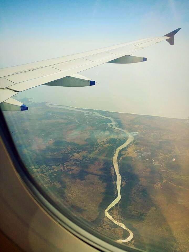 CROPPED IMAGE OF AIRPLANE WING OVER LANDSCAPE