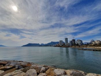 Sea by buildings against sky