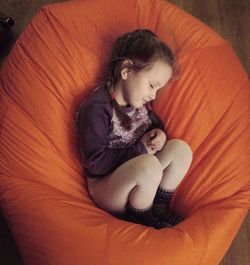 High angle view of girl sleeping on orange bean bag at home