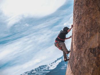 Man climbing on rock against sky
