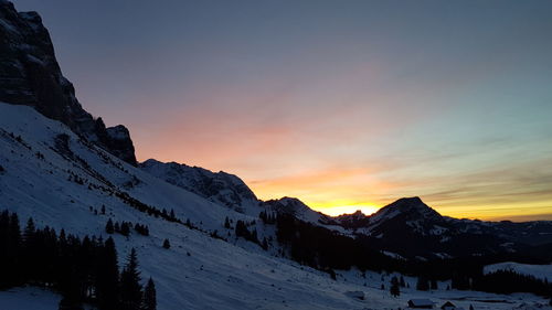 Scenic view of snowcapped mountains against sky during sunset