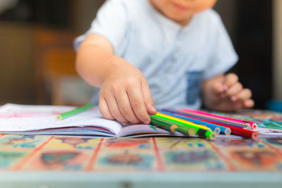 Midsection of boy drawing on table at home