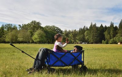 Friends sitting on field against sky