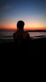 Silhouette woman on beach against clear sky during sunset