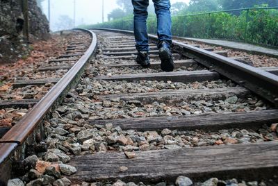 Low section of man walking on railroad track