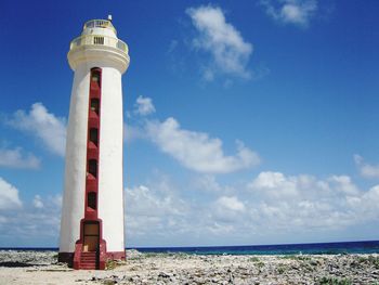 Lighthouse on shore against cloudy sky