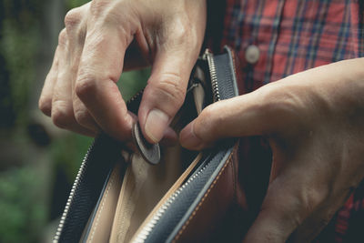 Midsection of man putting coin in wallet